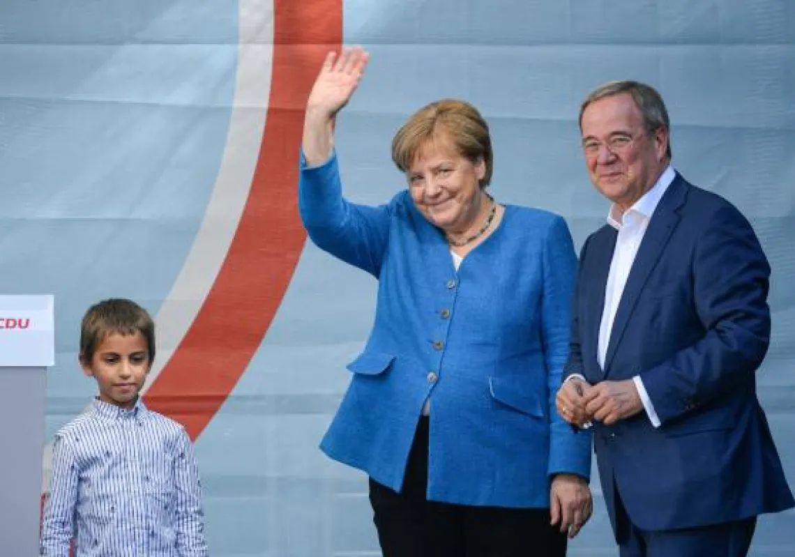 Christian Democratic Union CDU leader and chancellor candidate Armin Laschet (R) and German Chancellor Angela Merkel react on stage during their campaign rally in Aachen, western Germany, on September 25, 2021, one day ahead of the German federal elections. (Photo by Ina Fassbender / AFP)