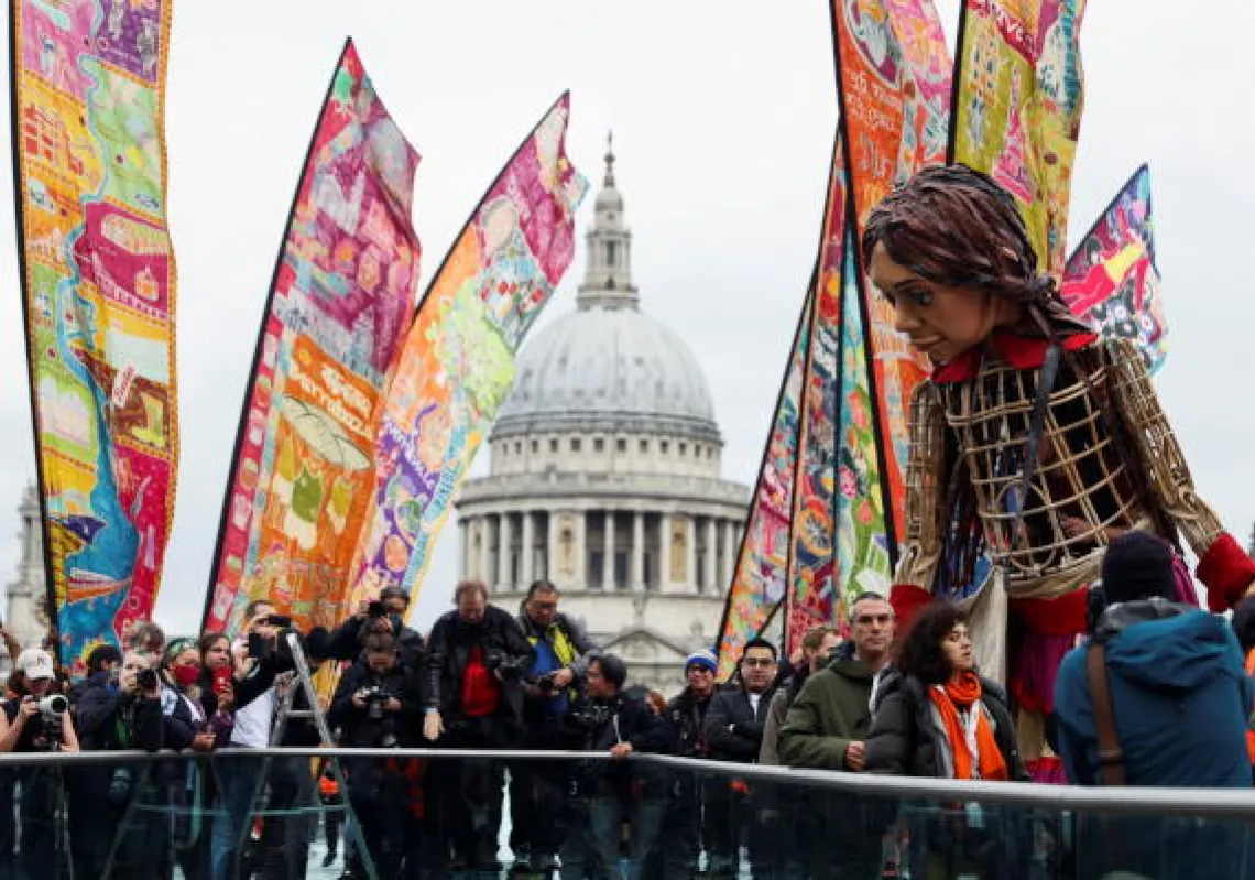 People gather around "Little Amal", a 3.5 metre tall puppet of a young Syrian refugee girl, as part of its 8,000 km tour across Europe from Turkey to Britain to raise awareness for the plight of young refugees, in London, Britain, October 23, 2021. REUTERS/Tom Nicholson