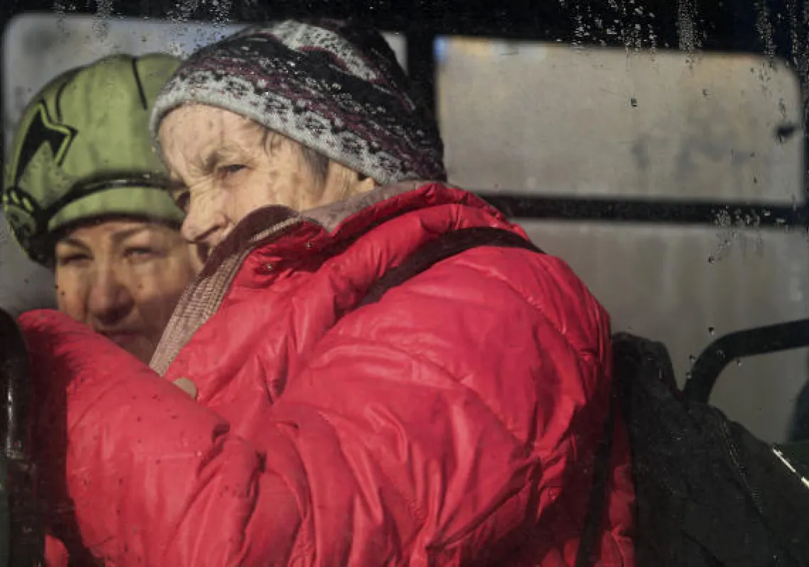 Two women are seen through a bus window, waiting to be evacuated to Russia, in Donetsk, the territory controlled by pro-Russian militants, eastern Ukraine, Saturday, Feb. 19, 2022.(AP Photo/Alexei Alexandrov)