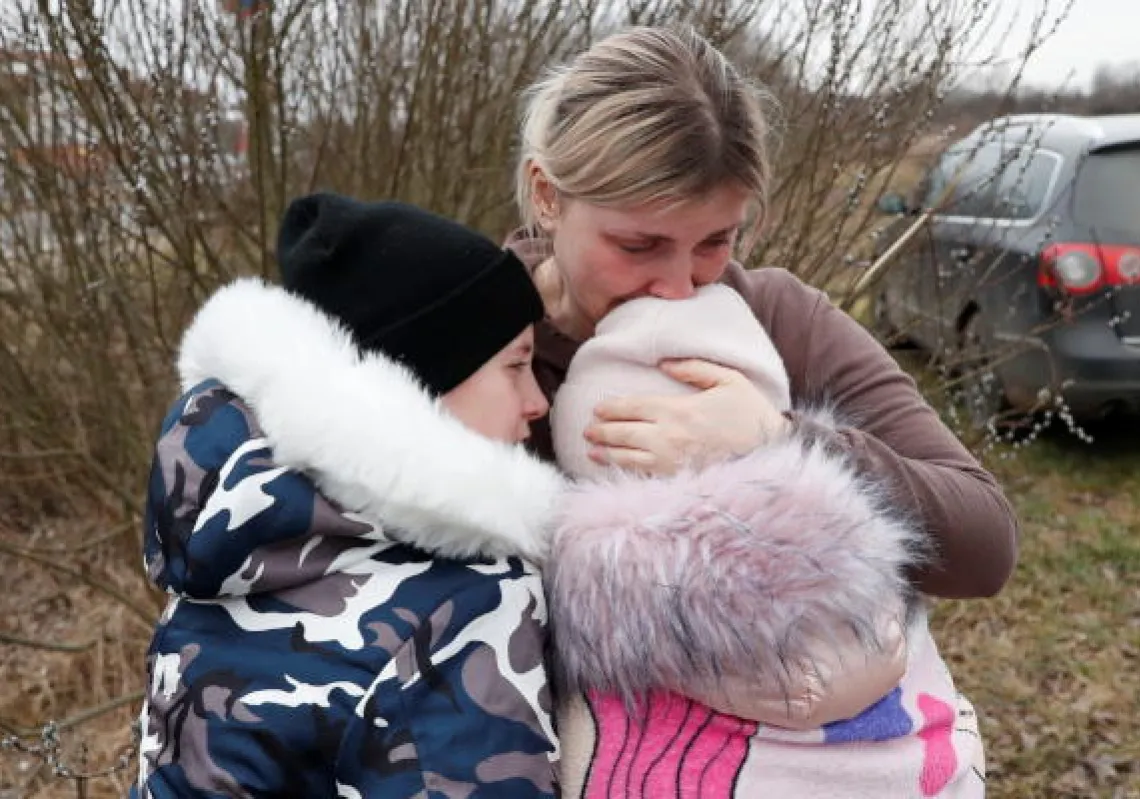 Anna Semyuk, 33, hugs her children, after a stranger took them across the border and kept them safe while fleeing from Ukraine and arriving in Hungary, after Russia launched a massive military operation against Ukraine, at the Beregsurany border crossing, Hungary, February 26, 2022. REUTERS/Bernadett Szabo