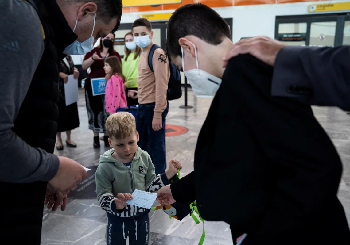 Gregorio Ripa, 10, hands Artem Nazarii, 3, a welcome note as the Nazarii family arrive at the Tijuana International Airport in Tijuana, Mexico April 15, 2022. REUTERS/Toya Sarno Jordan
