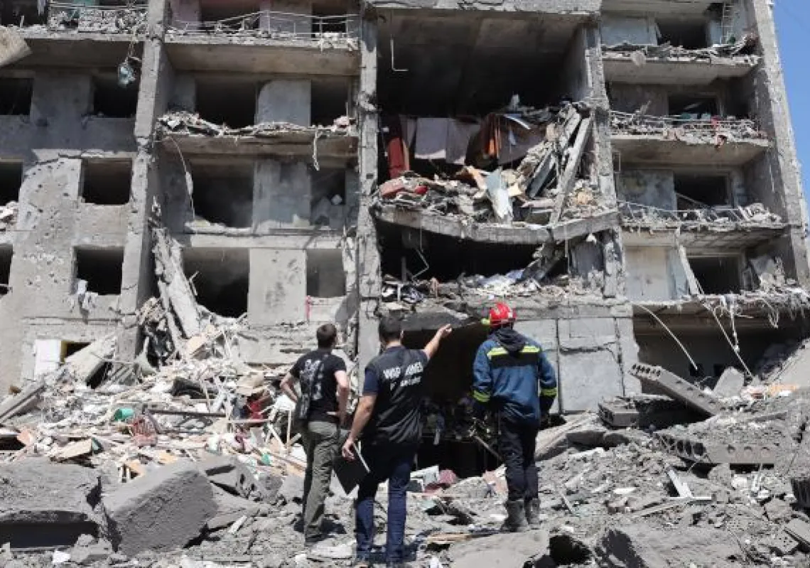 A war crimes prosecutor (C) and a rescuer (R) and a civil, look at a destroyed building after being hit by a missile strike in the Ukrainian town of Sergiyvka , near Odessa, killing at least 18 people and injuring 30, on July 1, 2022. - During the night from June 30 to July 1, 2022, two missiles were fired by a "strategic aircraft" from the Black Sea, hitting buildings, according to the Ukrainian emergency services. (Photo by Oleksandr GIMANOV / AFP)