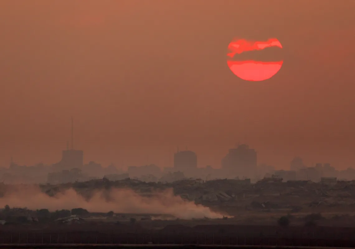 Smoke rises from an Israeli strike as the sun sets behind destroyed buildings in the Gaza Strip, on July 21, 2025. 