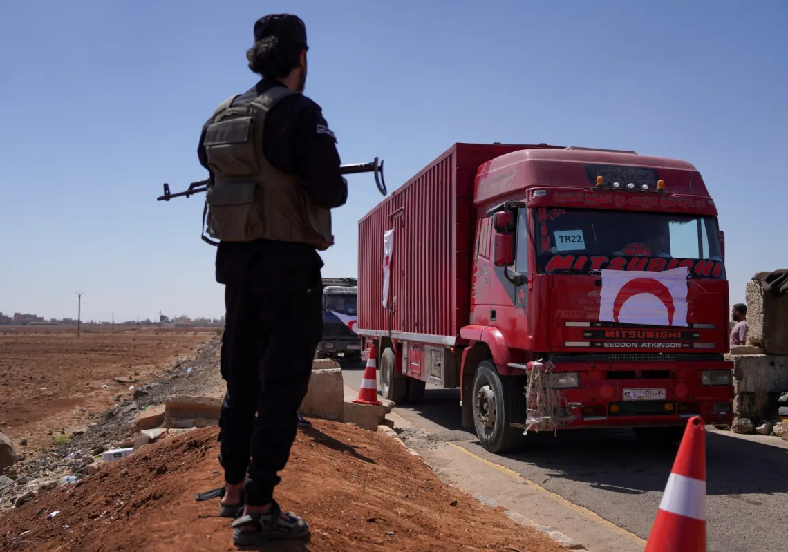 A member of Syrian security forces stands near a vehicle carrying aid as they make their way to Suweida, at Bosra al-Sham town, near Deraa, Syria July 23, 2025.