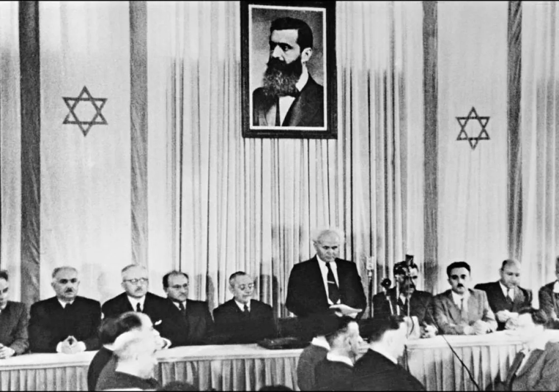 On May 14, 1948, Israeli Prime Minister David Ben-Gurion (standing under a huge portrait of Theodor Herzl, the founder of political Zionism, proclaims the establishment of Israel.