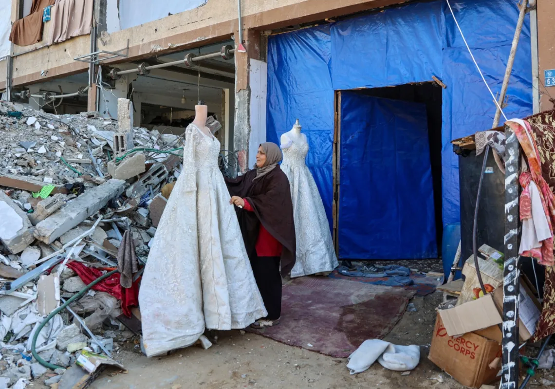 فلسطينية تبيع فساتين زفاف في متجر مؤقت بجوار أنقاض مبانٍ مدمرة في جباليا شمال غزة، 27 شباط 2025