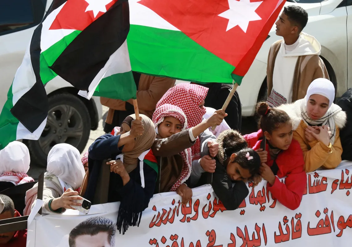 People wave flags as they gather along the road leading to Amman&#039;s Marka Airport to welcome King Abdullah II upon his return on February 13, 2025, from Washington, DC, where he met with US President Donald Trump.