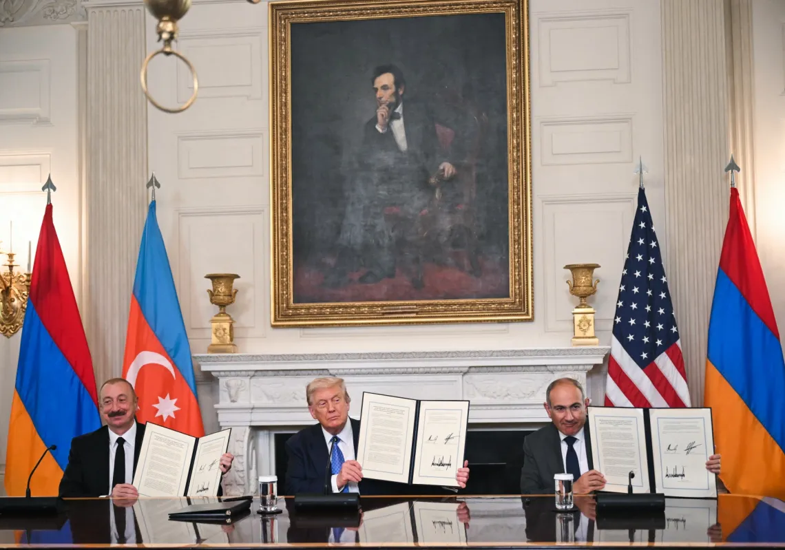 US President Donald Trump (C), Azerbaijani President Ilham Aliyev (L) and Armenian Prime Minister Nikol Pashinyan display the agreement they signed in the State Dining Room of the White House in Washington, DC, on August 8, 2025.