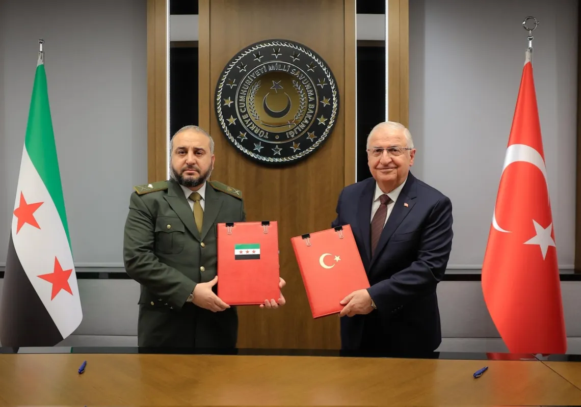 Syrian Defence Minister Murhaf Abu Qasra and Turkish Defence Minister Yaşar Güler hold up an MOU on security cooperation in Ankara on August 13, 2025.