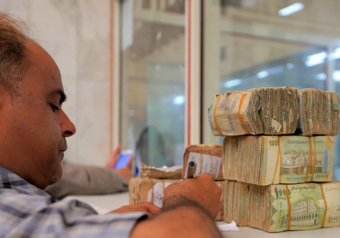 موظف في البنك المركزي اليمني بجوار مبالغ من العملة اليمنية في مقر البنك في العاصمة صنعاء في 23 يونيو 2021