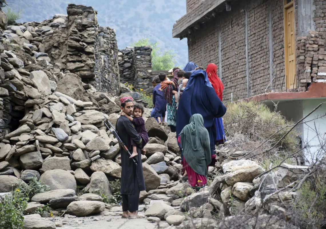 Local residents walk past a house destroyed by an earthquake that killed nearly 1,000 people and devastated villages in eastern Afghanistan, on September 1, 2025.