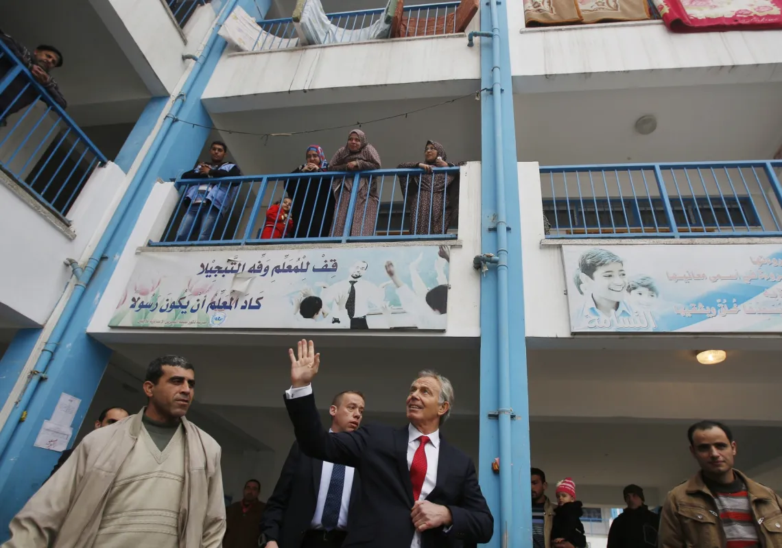 Middle East Quartet envoy Tony Blair (C) waves as he leaves a UN-run school sheltering Palestinians, whose houses were destroyed by Israeli airstrikes during the 2014 war, in Gaza City on February 15, 2015.