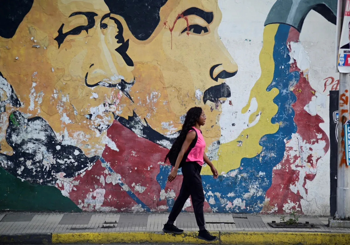 A woman walks past a mural depicting late former Venezuelan President Hugo Chavez and Venezuelan President Nicolas Maduro in Caracas, Venezuela July 27, 2024. 