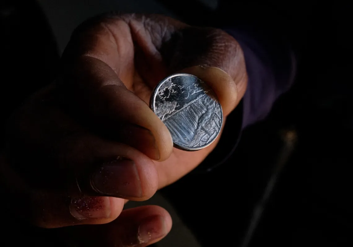 A customer receives the new $5 ZiG, short for Zimbabwe Gold, coins as change from a cashier in a leading supermarket in Harare on April 30, 2024.