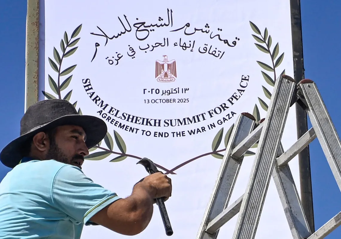 عامل مصري يثبت شعار "قمة شرم الشيخ - اتفاق انهاء الحرب في غزة" في احد شوارع المدينة في 12 اكتوبر  