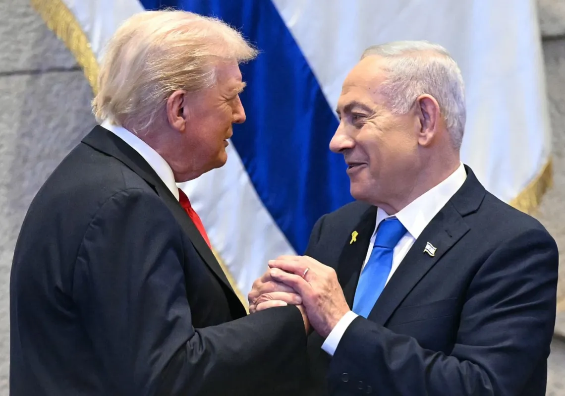 
الرئيس الأميركي دونالد ترمب يمسك بيد رئيس الوزراء الإسرائيلي بنيامين نتنياهو  في البرلمان الإسرائيلي (الكنيست) بالقدس في 13 أكتوبر 2025