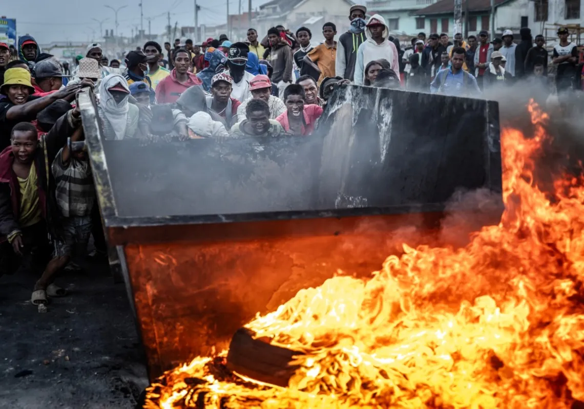 Protesters push a metal container to use as a barricade during clashes with security forces amid a strike calling for constitutional reforms and the resignation of President Andry Rajoelina in Antananarivo, on October 9, 2025.
