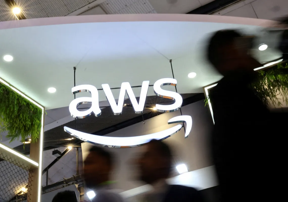 يمر الناس أمام شعار شركة "أمازون ويب سيرفيسز" (AWS) في جناح معرضها في مؤتمر الهند للهواتف المحمولة 2025