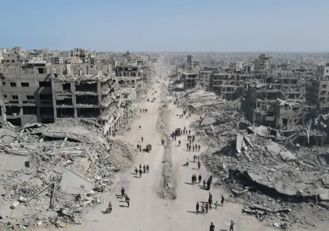 People walk amid the destruction in Gaza City in the northern Gaza Strip on October 11, 2025, a day after a ceasefire took effect.