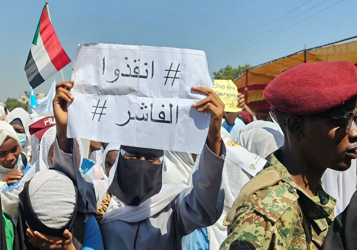 
امرأة سودانية تحمل لافتة كُتب عليها باللغة العربية &quot;#أنقذوا_الفاشر&quot; خلال احتجاج منظم ضد انتهاكات قوات &quot;الدعم السريع&quot; بحق أهالي الفاشر، في مدينة القضارف شرقي السودان، في 6 نوفمبر 2025