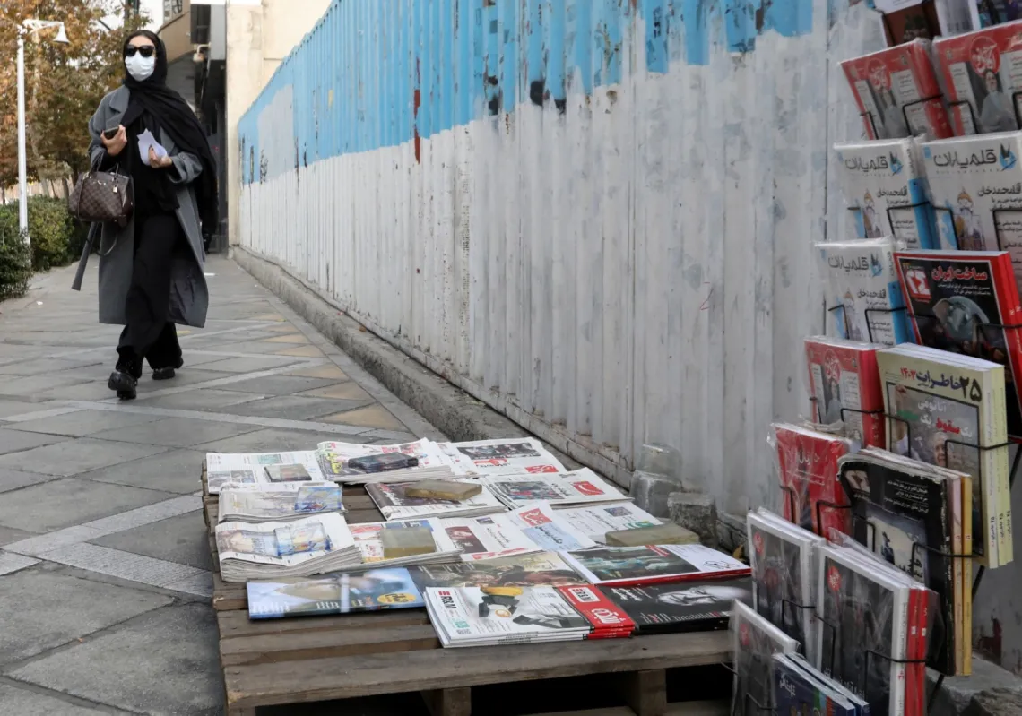 امرأة إيرانية تمر أمام كشك لبيع الصحف المحلية، وفي 8 ديسمبر 2024.