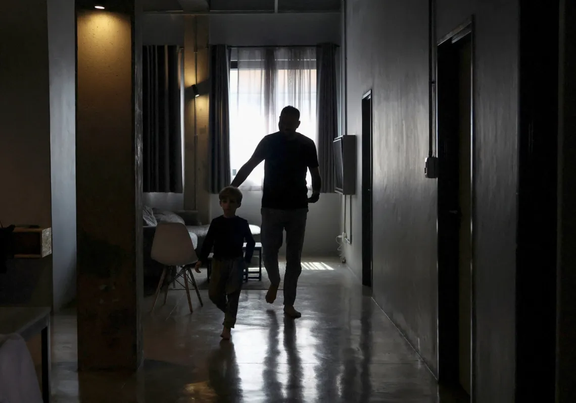 A Palestinian man walks with his child after speaking to Reuters at an undisclosed location in Johannesburg, South Africa after being transfered from Gaza via Israel on 14 November, 2025.