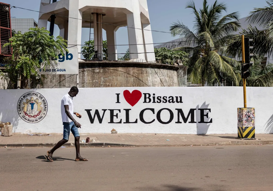 أحد المشاة أمام جدارية كُتب عليها "أحب بيساو"، في 27 نوفمبر2025