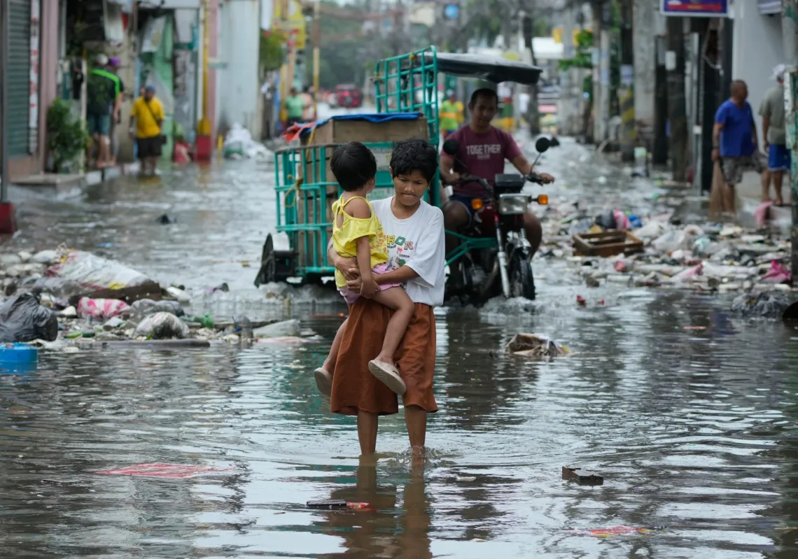 امرأة وطفل يعبران شارعا غمرته المياه بسبب إعصار فونغ وونغ وارتفاع المد، في نافوتاس، الفيليبين، 10 نوفمبر