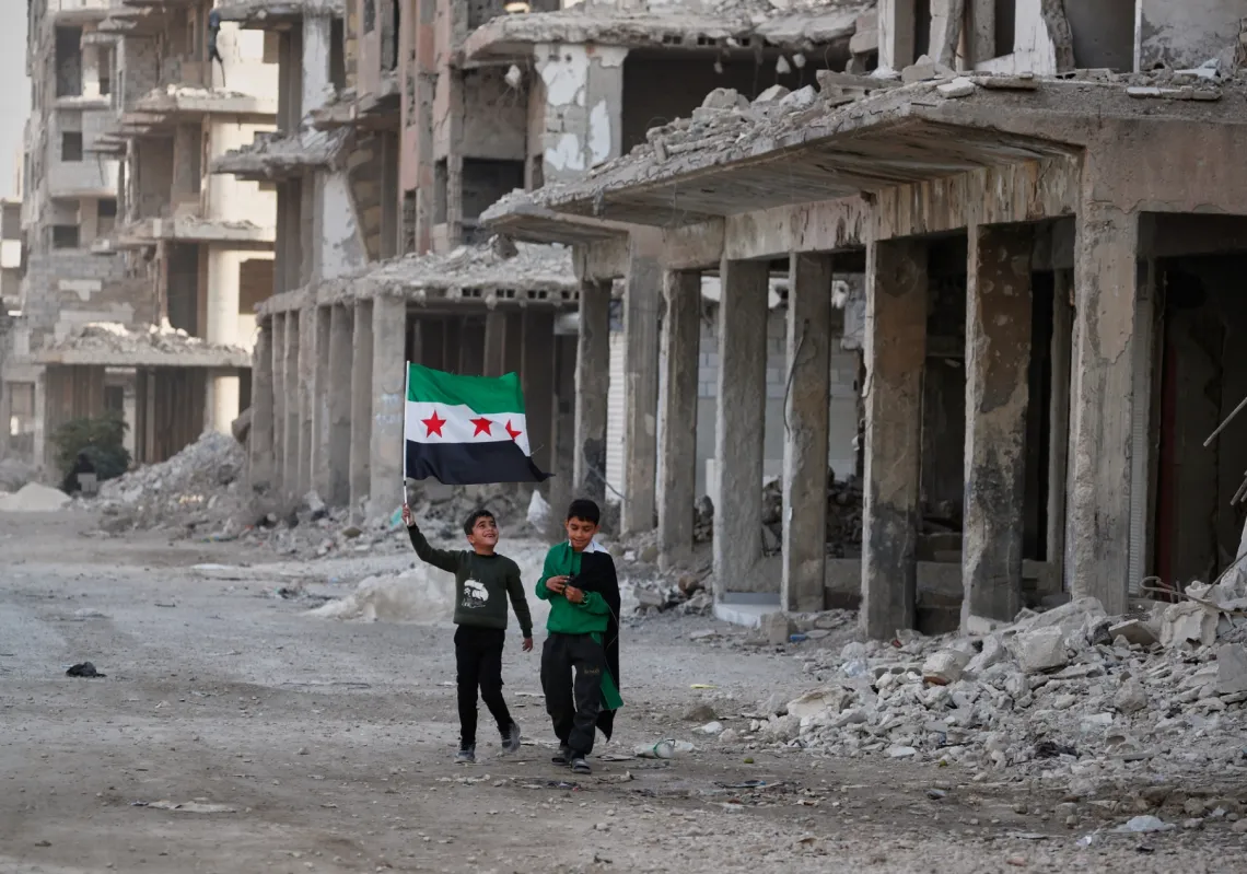 طفلان يحملان علما سوريا في ضاحية داريا في 5 ديسمبر قبيل الاحتفالات بالذكرى الاولى لسقوط بشار الاسد  