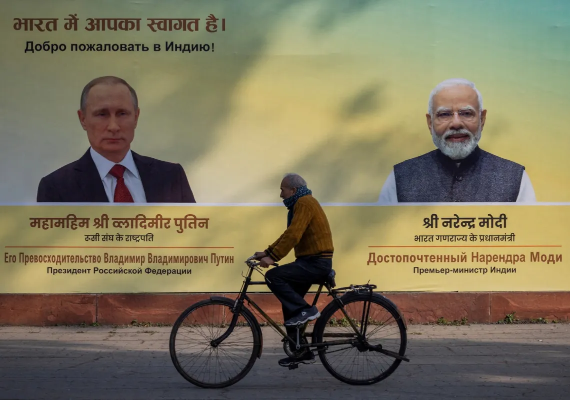 رجل على دراجة امام صورتين لرئيس الوزراء الهندي ناريندرا مودي والرئيس الروسي فلاديمير بوتين في نيودلهي في 4 ديسمبر 