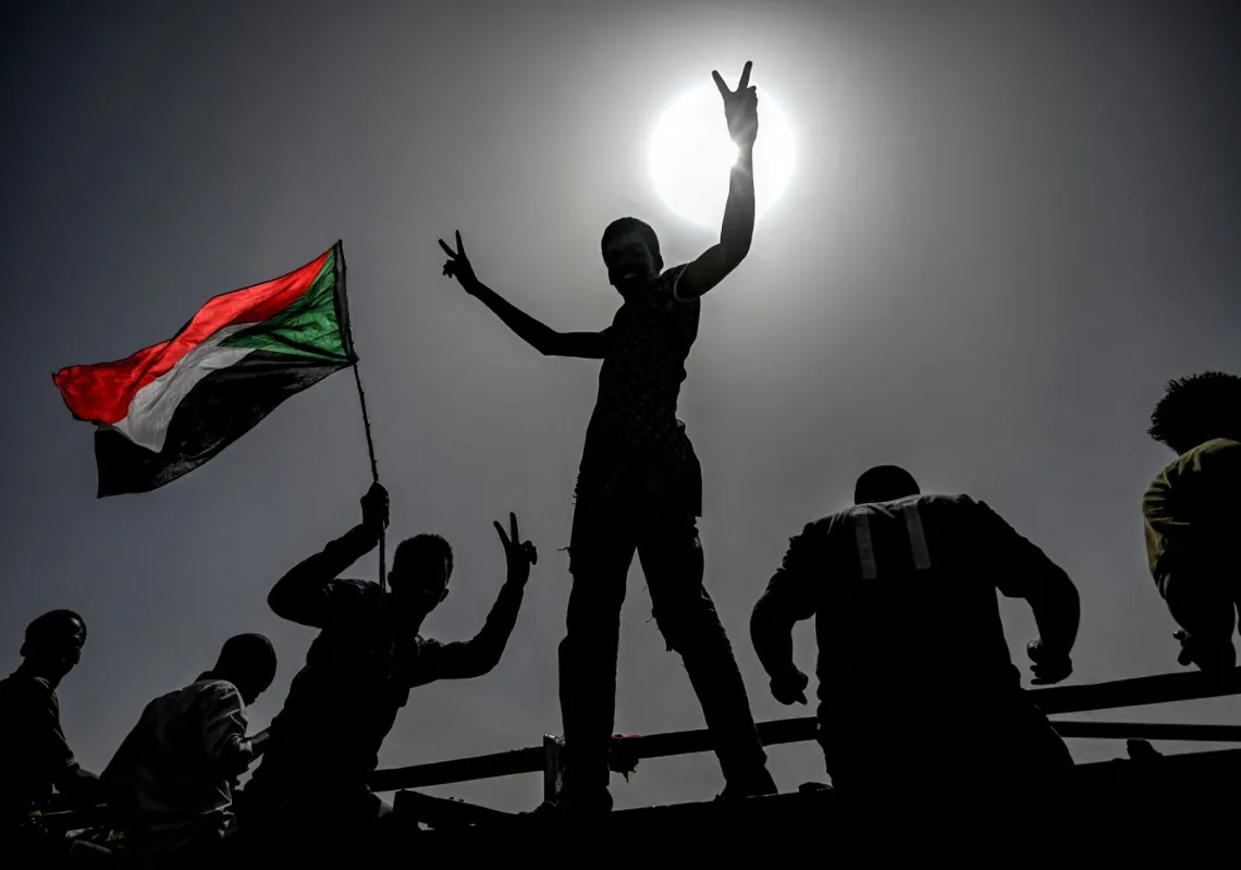متظاهرون سودانيون يلوحون بالأعلام ويرفعون علامات النصر أثناء احتجاجهم أمام مقر الجيش في العاصمة الخرطوم، في 17 أبريل 2019
