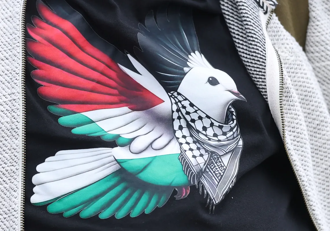 حمامة ترمز إلى السلام بألوان العلم الفلسطيني تظهر على قميص أحد المتظاهرين خلال مسيرة نظّمتها حملة التضامن مع فلسطين أمام مكاتب لوكهيد مارتن في بريطانيا، للمطالبة بحظر تسليح إسرائيل، 8 أكتوبر 2025