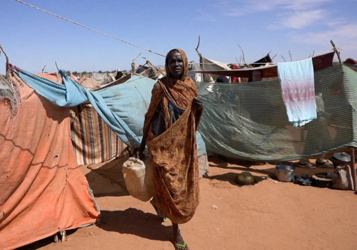 A displaced Sudanese woman who was held by the Rapid Support Forces (RSF) carries a water container at a camp for displaced people who fled from El-Fasher to Tawila, North Darfur, Sudan, on 15 November 2025. 