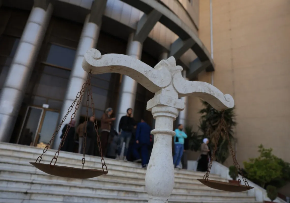 People stand outside the Justice Palace after first trial of more than a dozen suspects linked to massacres that left hundreds dead in Syria's Alawite coastal heartland earlier this year, in Aleppo on 18 November 2025.
