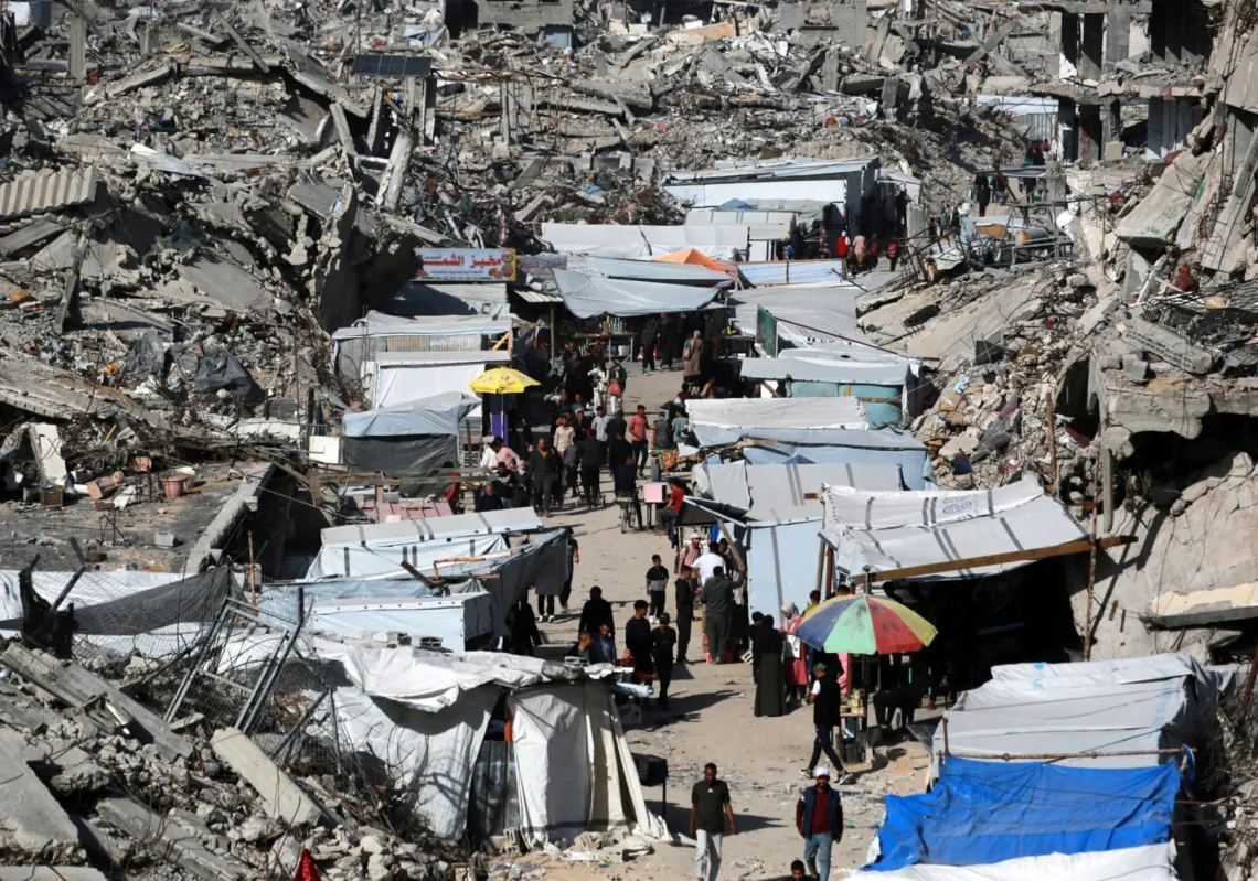 لقطة جوية تُظهر فلسطينيين متجمعين في سوق مؤقت أُقيم وسط حي دمّرته الحرب في مخيم جباليا للاجئين شمال قطاع غزة