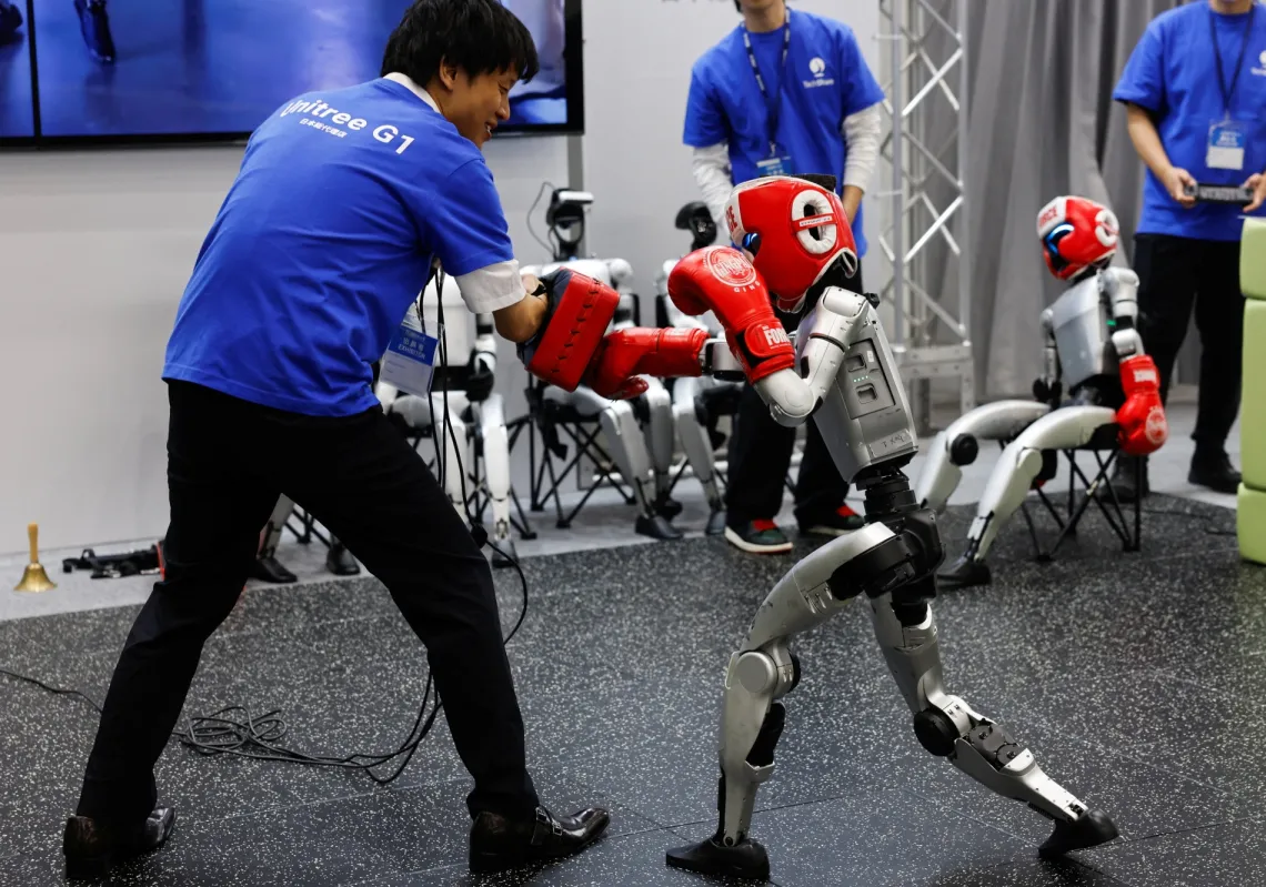 روبوت Unitree G1 ذو الشكل البشري يتنافس مع إنسان في جناح TechShare في المعرض الدولي للروبوتات 2025 في Tokyo Big Sight في طوكيو، اليابان، 3 ديسمبر