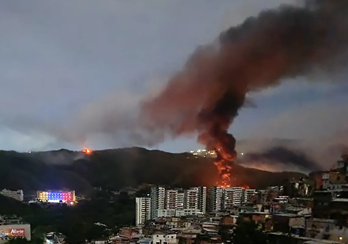 Fire at Fuerte Tiuna, Venezuela's largest military complex, is seen from a distance after a series of explosions in Caracas on 3 January 2026. 