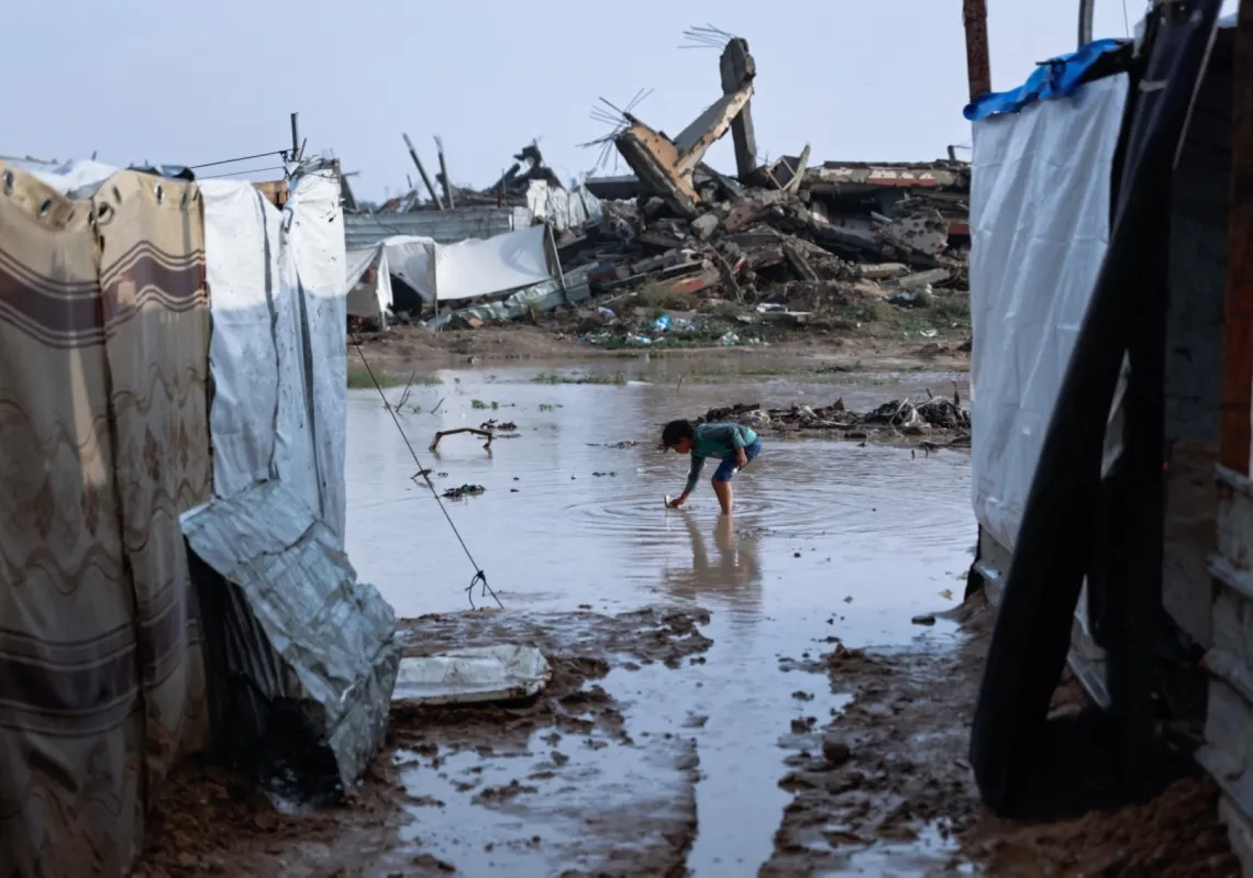 فتاة تقف في بركة ماء بمخيم مؤقت للنازحين الفلسطينيين بعد هطول أمطار غزيرة في حي الزيتون بمدينة غزة في 11 ديسمبر 2025