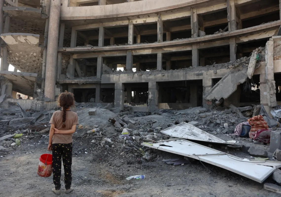 فتاة فلسطينية أمام مركز الشيخ رضوان الصحي التابع لوكالة (الأونروا) شمال مدينة غزة في 6 أغسطس 2025، بعد غارة جوية وقصف جوي إسرائيلي