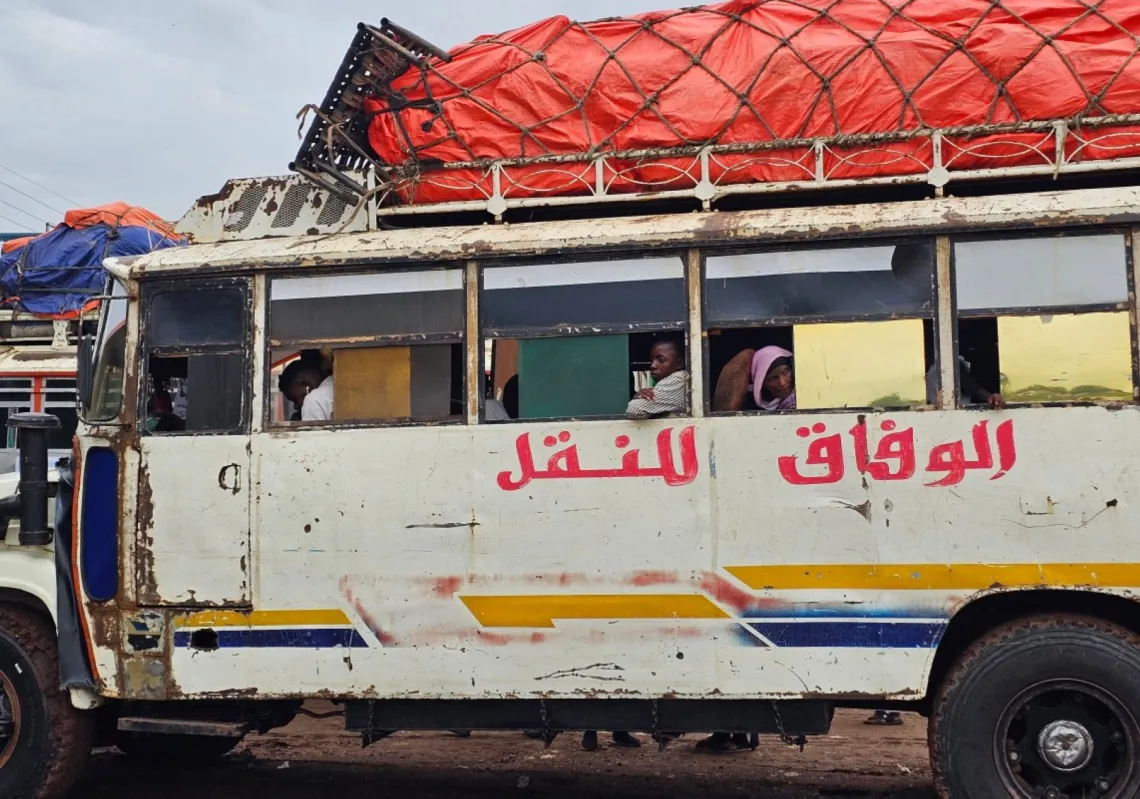 Displaced Sudanese arrive at a bus stop in Khartoum on 28 July 2025, upon their return to the capital. 