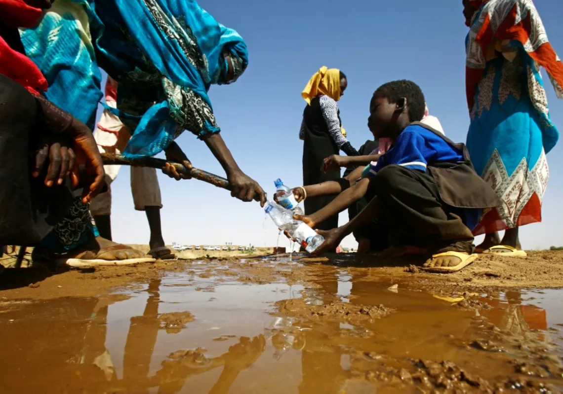 امرأة سودانية تملأ زجاجات المياه التي يحملها صبي صغير على بعد حوالي 60 كيلومترًا شمال الفاشر، عاصمة ولاية شمال دارفور، في 9 فبراير 2017