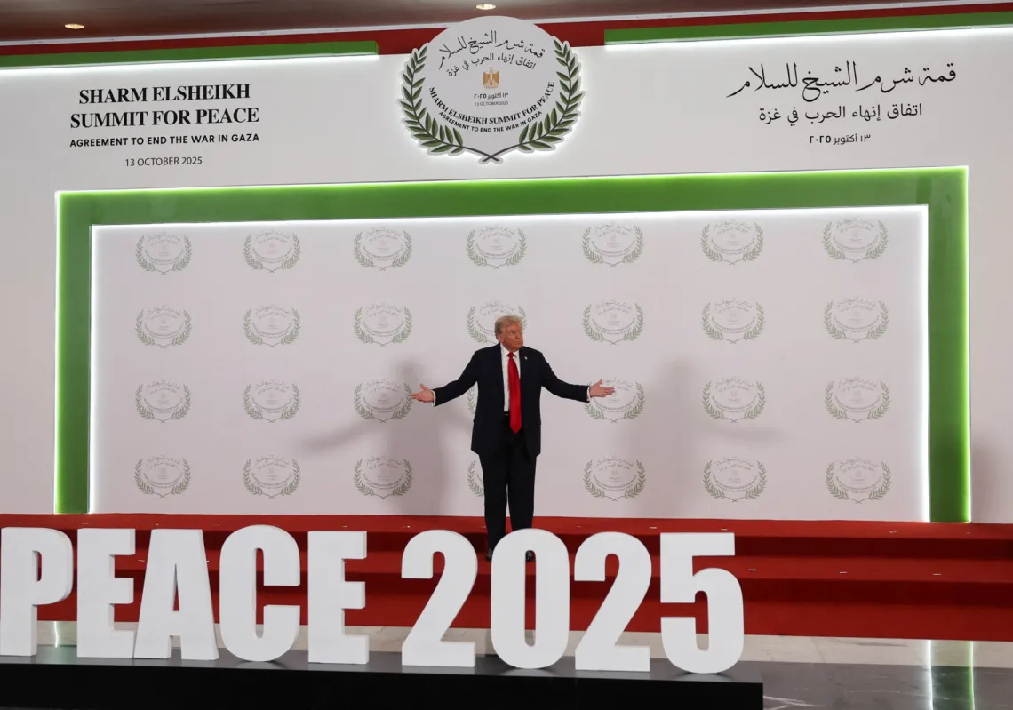 الرئيس الأميركي دونالد ترمب يقف أمام لافتة في قمة قادة العالم لإنهاء حرب غزة، في شرم الشيخ، مصر، 13 أكتوبر 2025