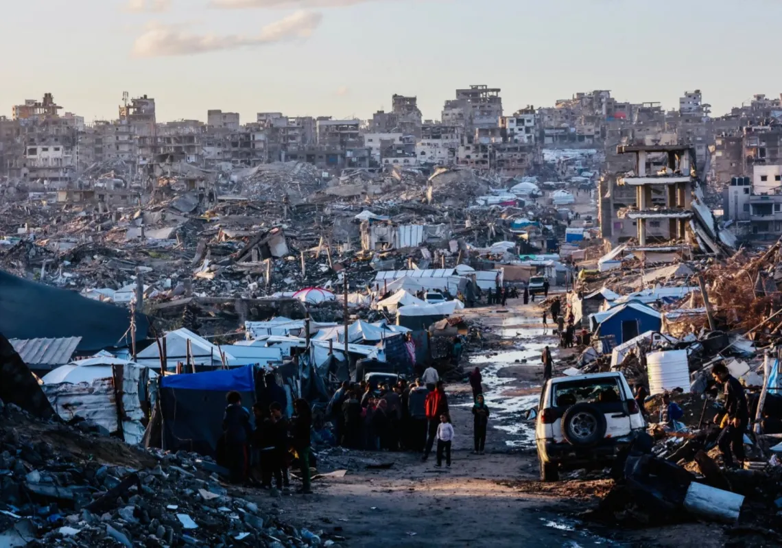 نازحون فلسطينيون يقفون على طريق غمرته مياه الأمطار في مدينة جباليا شمال قطاع غزة، 25 نوفمبر 2025
