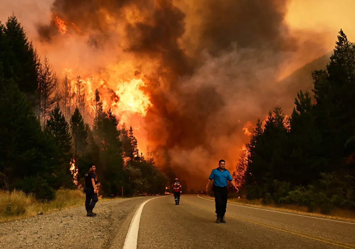 People walk on a road as a wildfire blazes in El Hoyo, Patagonia, Argentina, on 8 January 2026. 