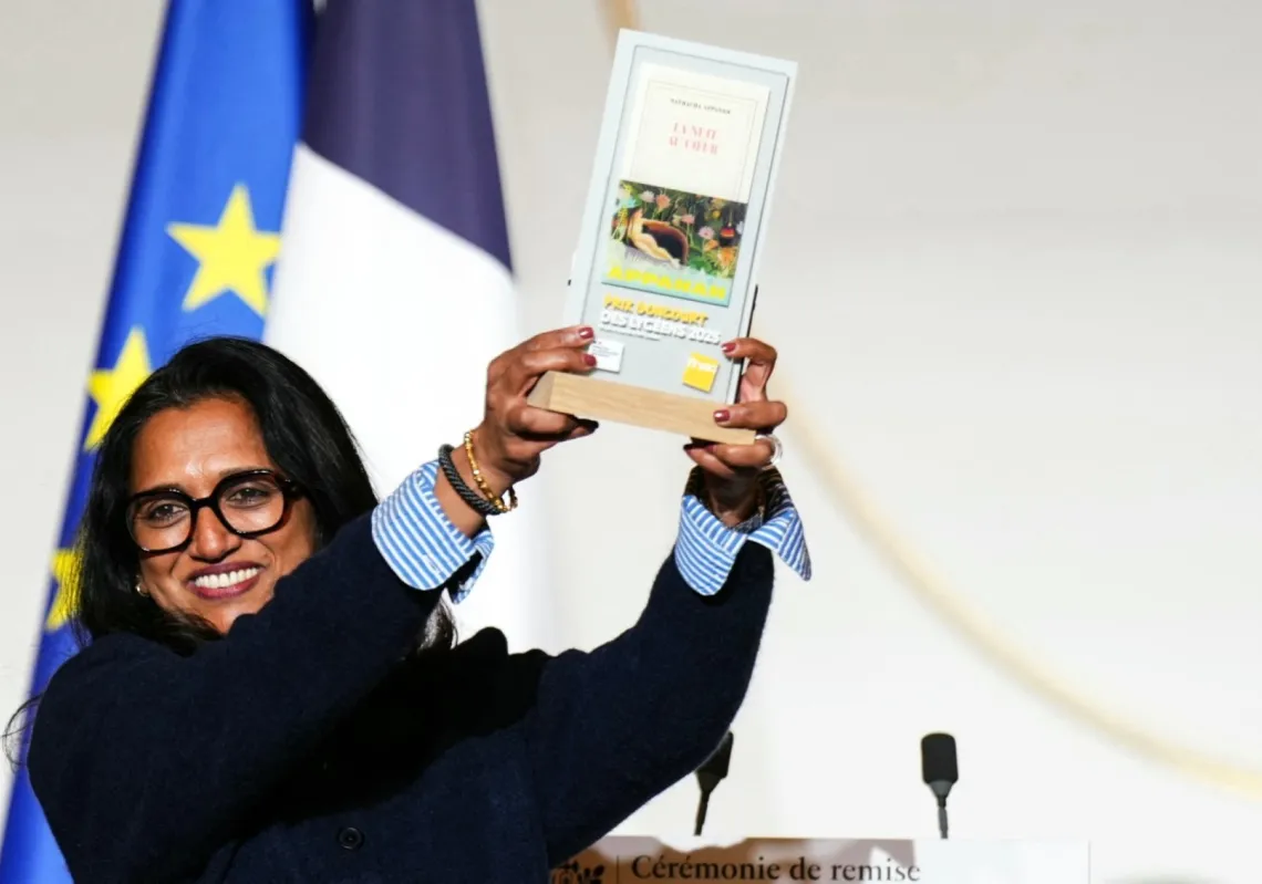 الكاتبة الموريشيوسية-الفرنسية ناتاشا أبانا تحمل روايتها "الليل في القلب" بعد فوزها بجائزة «Prix Goncourt des Lycéens 2025» خلال حفل توزيع الجوائز في قصر الإليزيه في باريس، 27 نوفمبر 2025