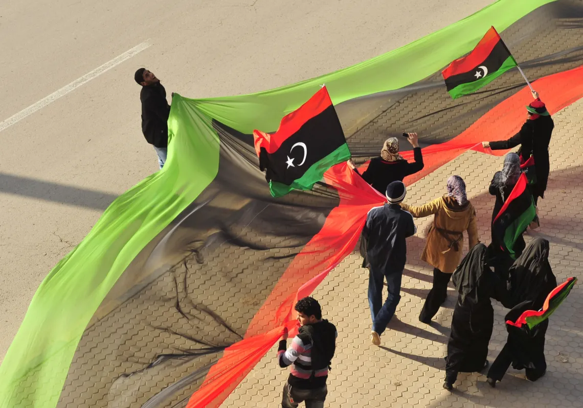 ليبيون يرفعون علم بلدهم احتفالاً بالذكرى السنوية الأولى للانتفاضة التي أطاحت بمعمر القذافي، في أحد شوارع بنغازي في 17 فبراير 2012