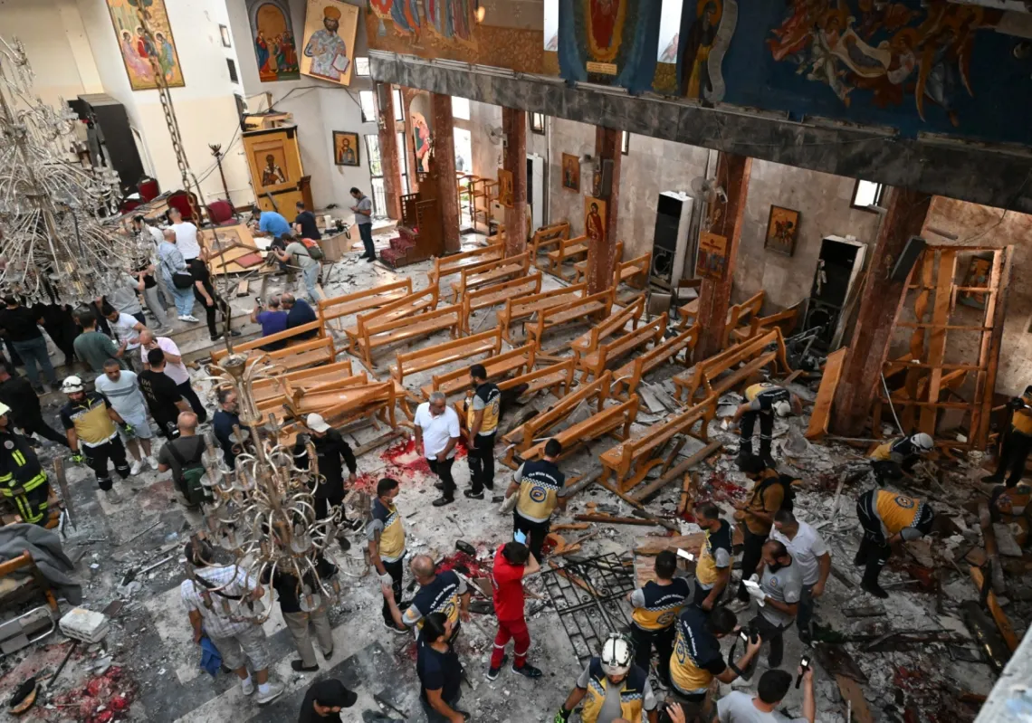 People and rescuers inspect the damage at the site of a reported suicide attack at the Saint Elias church in Damascus' Dwelaa area on 22 June 2025. 