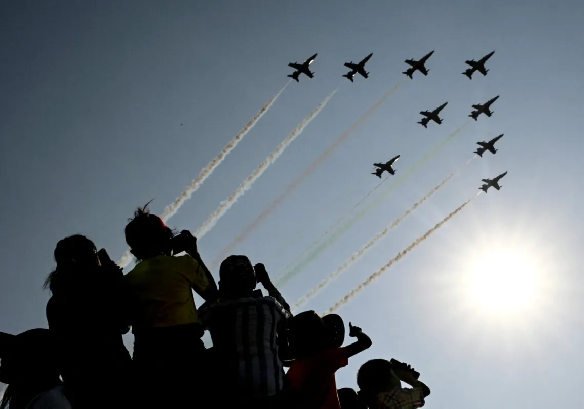 Children watch the Indian Air Force (IAF) Surya Kiran aerobatics team performing during Aero India 2025, a military aviation exhibition at the Yelahanka Air Force Station in Bengaluru on 13 February 2025. 