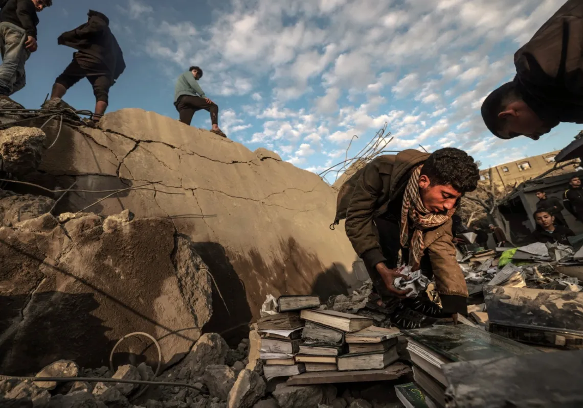 Palestinian youth retrieve books from the rubble of a mosque and buildings which collapsed during Israeli bombardment around the town city of Rafah southern Gaza Strip on 24 January 2024.
