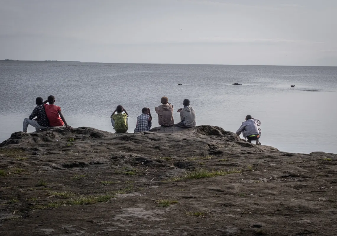 
مجموعة من الصبية يراقبون بفضول أفراس النهر وهي تقترب من شواطئ بحيرة ديمبل، إحدى بحيرات وادي الصدع الأوسط في إثيوبيا التي تأثرت لفترة طويلة بالاستخدام المفرط والتلوث، في باتو في 22 مايو 2025.